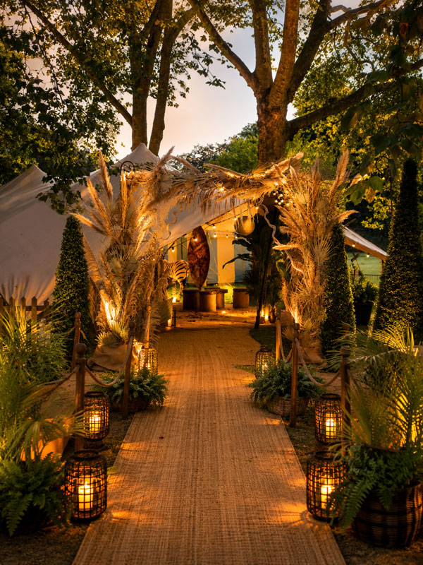 Luxury safari themed awards ceremony entrance featuring a bespoke decorative archway, illuminated pathway, tropical planting, lantern lighting and immersive event styling for a corporate awards event.